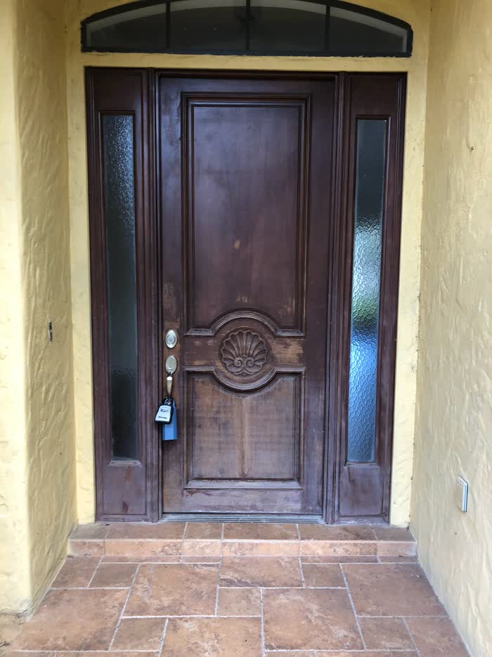 A faded brown front door with a carved shell medallion, flanked by two narrow frosted-glass panels.