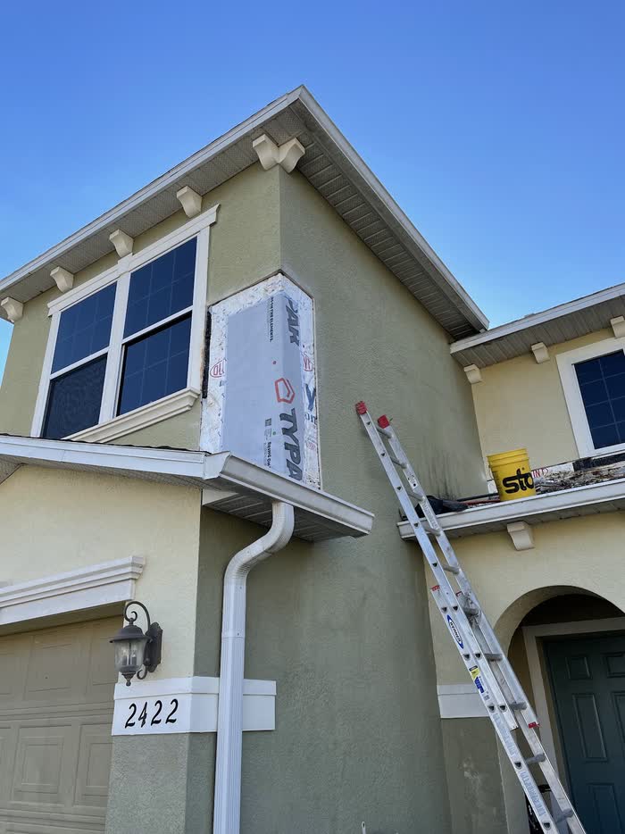 The narrow opening beside the upstairs window is now closed with a white panel, ladder leaning nearby.
