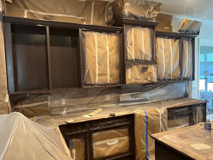 Masked dark cabinets along one wall, upper shelves emptied, plastic sheeting draped across the counter below.