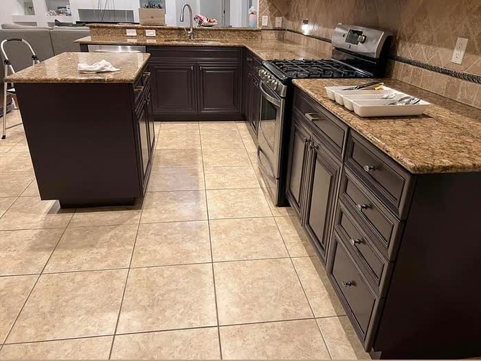 Kitchen island and matching dark base cabinets with round drawer handles, seen across the tiled floor.