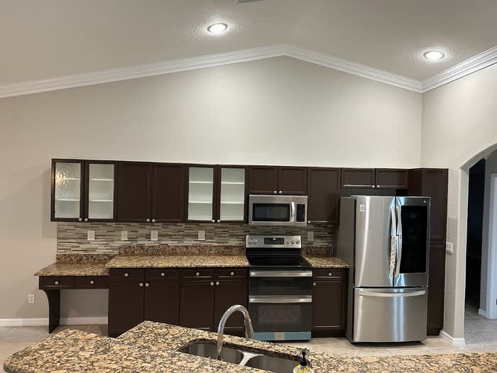 Finished kitchen with dark brown cabinets, a tiled backsplash and stainless steel appliances.