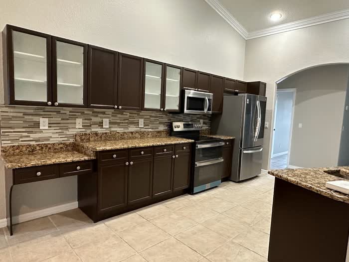 Wide view along a run of dark brown cabinets, with a built-in desk nook at the near end.