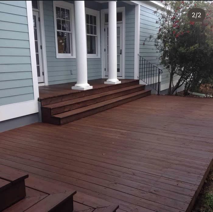 Deep reddish brown boards cover the same deck, below white porch columns and pale blue walls.