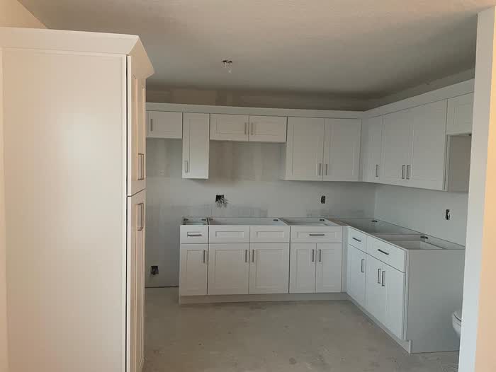 White cabinets newly hung in an unfinished kitchen, with no counters in place yet.