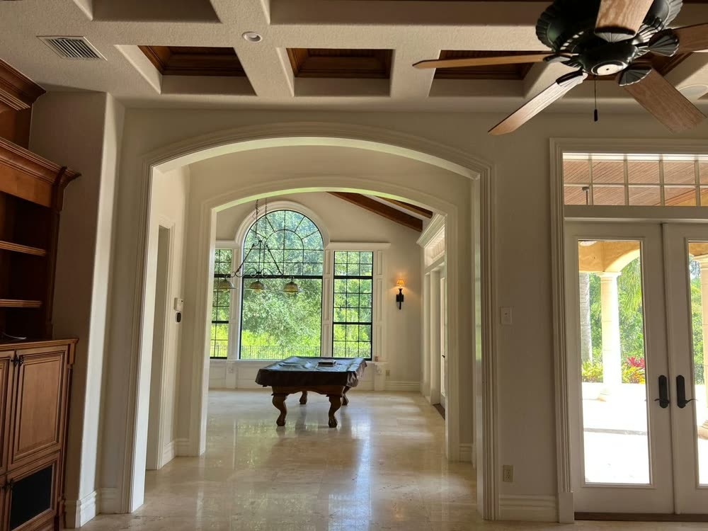 A coffered ceiling and a wide arched opening looking through to a games room beyond.