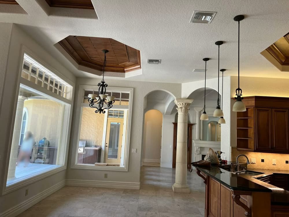 An open kitchen and living space with a column, arched openings and a recessed ceiling.