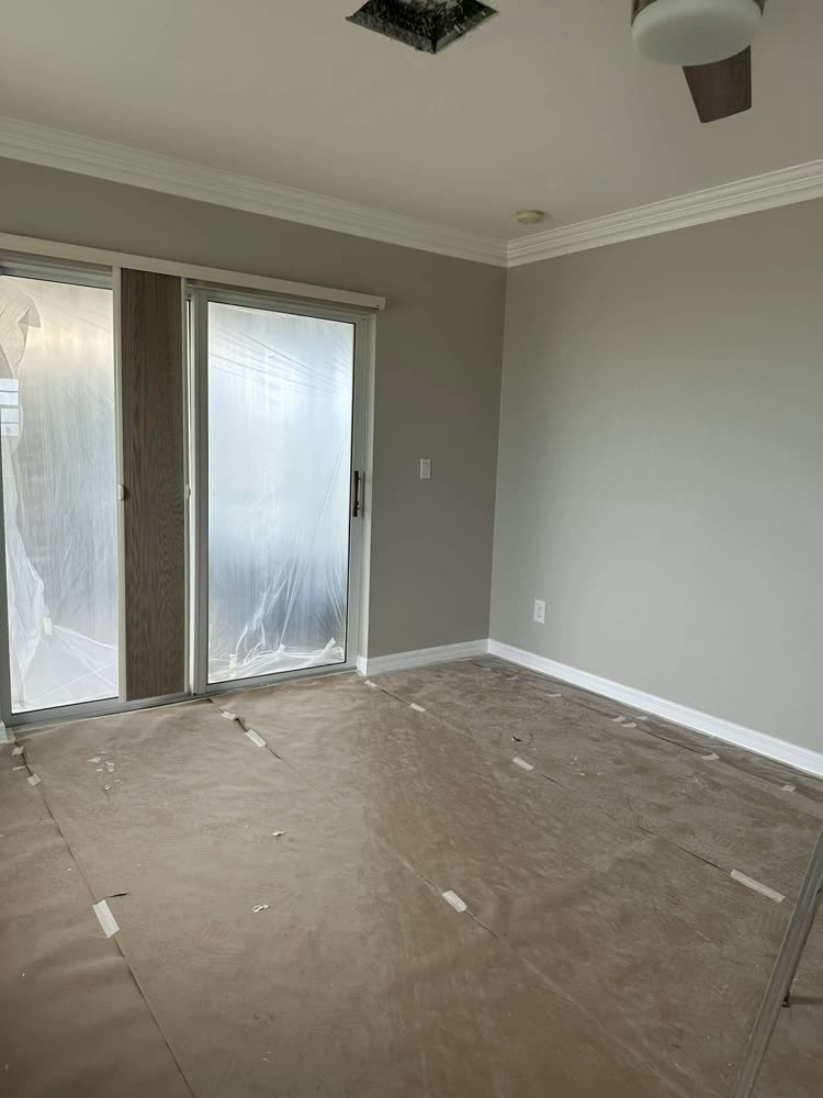 A repainted room with a sliding door masked off and the floor papered and taped down.