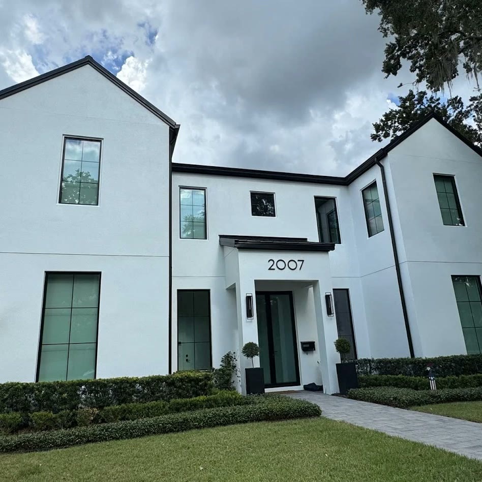 A large two-storey home finished in white with black window frames and
                    twin gables, seen from the front path.